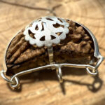 Side view of 1 Mukhi Rudraksha (Kaju Dana) placed on a wooden block with a blurred background, showing its smooth, singular surface and natural texture.