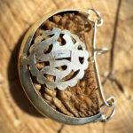 Top view of 1 Mukhi Rudraksha (Kaju Dana) placed on a wooden block with a blurred background, highlighting its smooth, single-faced surface.