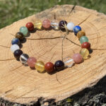 9 Planet crystal bracelet placed on a wooden block with a blurred garden background.