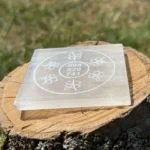Side-angle view of Grabovoi code engraved Selenite charging plate resting on a wooden surface
