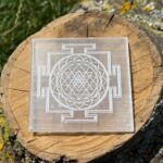 Front faced photo of Shree Yantra Selenite charging plate placed on a wooden block showing engraved sacred geometry